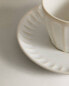 Stoneware teacup and saucer with raised design