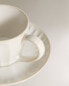 Stoneware teacup and saucer with raised design