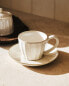 Stoneware teacup and saucer with raised design